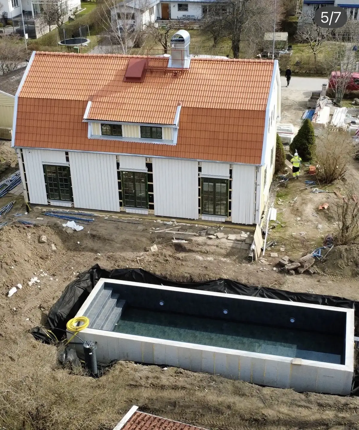 Flygbild över poolprojekt i Täby — pool bredvid villa med orange tak