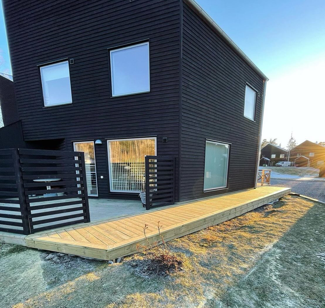 Nybyggd altan i trä vid svart villa i Österåker